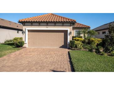 Tan house with tile roof, 2-car garage, and landscaped yard at 3312 Francoa Dr, Odessa, FL 33556