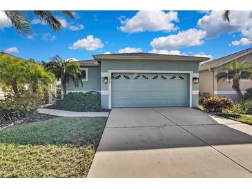 House exterior features a light teal color, two-car garage, and landscaping at 8148 Ambersweet Pl, Land O Lakes, FL 34637