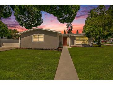 Updated one-story home with gray exterior, landscaped lawn, and walkway at 4602 W Hawthorne Rd, Tampa, FL 33611