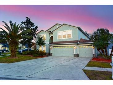 Two-story house with a three-car garage and landscaped lawn at 4634 Mapletree Loop, Wesley Chapel, FL 33544