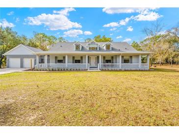 Gray house with wrap around porch and detached garage at 14325 Highgrove Rd, Brooksville, FL 34609