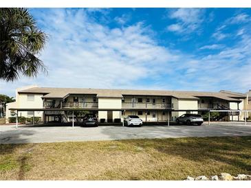 Two-story condo building with covered parking and lush landscaping at 4515 Marine Pkwy # 102, New Port Richey, FL 34652