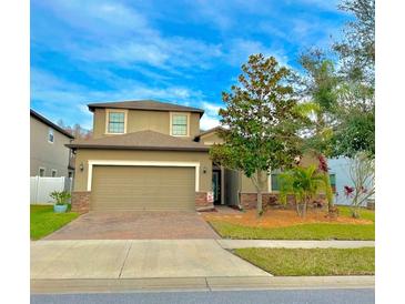 Two-story house with a green exterior, brick facade, and a two-car garage at 11777 Crestridge Loop, New Port Richey, FL 34655