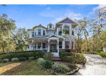 Two-story house with a wrap-around porch and landscaped yard at 22770 Skyview Cir, Brooksville, FL 34602