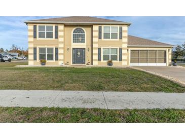 Two-story house with tan exterior, gray shutters, and a large front yard at 4332 Lamson Ave, Spring Hill, FL 34608