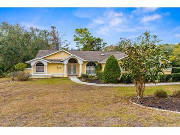 Single-story house with a yellow exterior, and landscaping at 555 Cressida Cir, Spring Hill, FL 34609