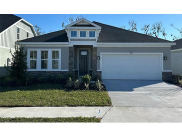 One-story home with gray siding, stone accents, and a two-car garage at 10131 Zennia Ln, Parrish, FL 34219
