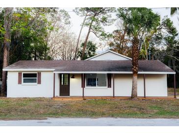 White single story home with brown trim, covered porch, and palm tree at 4852 Capron St, New Port Richey, FL 34653