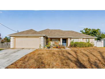 Tan one-story house with gray roof, attached garage, and landscaped yard at 4372 Odin St, Spring Hill, FL 34608
