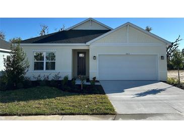 One-story home with white exterior, two-car garage, and landscaped front yard at 10123 Zennia Ln, Parrish, FL 34219