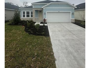 One-story home with light blue exterior, stone accents, and two-car garage at 10127 Zennia Ln, Parrish, FL 34219