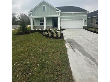 One-story home with light green exterior, two-car garage, and well-manicured lawn at 10135 Zennia Ln, Parrish, FL 34219