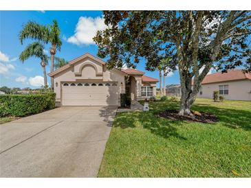 Charming single-story home featuring a red tile roof, manicured lawn, and mature landscaping at 1082 Dartford Dr, Tarpon Springs, FL 34688