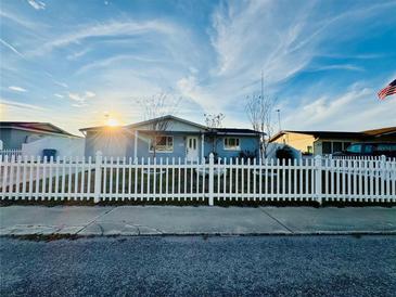 Charming single-story home featuring a white picket fence and a well-manicured lawn at 1415 Weyford Ln, Holiday, FL 34691