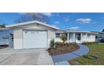 Newly renovated home with a landscaped front yard and a large driveway at 7815 Tyson Dr, Port Richey, FL 34668