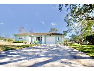 Cute light blue house with a white garage door and a yellow bicycle parked in the driveway at 9240 Tiara Ct, New Port Richey, FL 34655