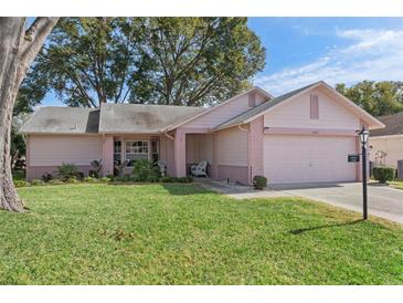 Pink one-story house with a two-car garage and well-maintained lawn at 2263 Whisper Walk Dr, Spring Hill, FL 34606