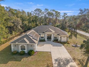 An aerial view of a charming single story home with a long concrete driveway and well-manicured landscaping at 7482 Winter St, Brooksville, FL 34613