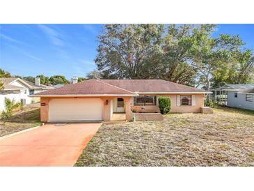 Charming single-story brick home featuring an attached garage and a well-maintained front yard at 8464 Dirlenton Way, Weeki Wachee, FL 34613