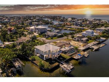 Breathtaking aerial view of waterfront homes on winding canals and open bay with a colorful sunset at 3383 Flamingo Blvd, Hernando Beach, FL 34607