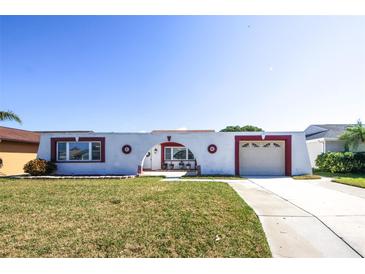 Unique single-story home with an arch detail over the entryway and garage, surrounded by a green lawn at 3526 Overland Dr, Holiday, FL 34691