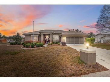 Charming single-story home featuring manicured landscaping, a two-car garage, and a warm, inviting entryway at 6112 Kinlock Ave, Spring Hill, FL 34608