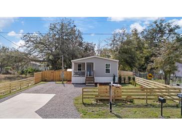 Charming home featuring a cozy front porch, a gravel driveway and a newly installed wooden fence at 9250 Peony St, New Port Richey, FL 34654