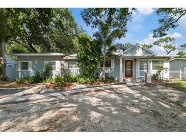 Charming single-story home featuring a red front door, light blue paint, stone trim, and lush landscaping at 1101 N Betty Ln, Clearwater, FL 33755