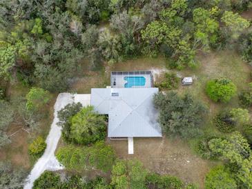 Aerial view of the home with a metal roof, a pool, and lush landscaping at 16411 County Road 675, Parrish, FL 34219