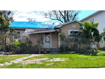 Exterior view of a single story home with a tarp covered roof and damaged front yard at 222 84Th N Ave, St Petersburg, FL 33702