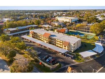 Aerial view of the condos with covered parking, a tennis court and beautifully landscaped grounds at 2440 Winding Creek Blvd # 305, Clearwater, FL 33761