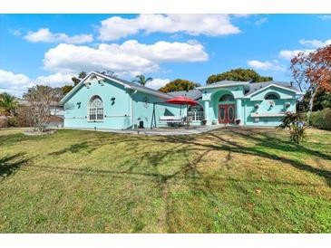 Charming turquoise home with a well-manicured lawn and a bright red front door, perfect for a Gathering at 2334 Gimlet, Spring Hill, FL 34608