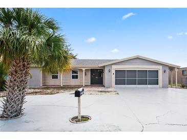 Charming single-story home with palm tree, gray accent, and a spacious driveway leading to a screened-in two-car garage at 3736 Sail Dr, New Port Richey, FL 34652