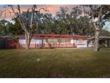 Charming single-story home with red tile roof, wooden fence, and lush front lawn at 4929 Avery Rd, New Port Richey, FL 34652