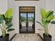 Modern front door with glass panels and tropical plants at 11826 River Shores Trl, Parrish, FL 34219