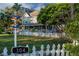 Quaint two-story home with a lush front lawn, a charming sign post, and a welcoming picket fence at 304 15Th W St, Bradenton, FL 34205