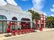 Outdoor seating area with red umbrellas and tables outside various shops at 430 Kumquat Ct # 310, Sarasota, FL 34236