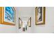 Long hallway adorned with framed artwork leading to staircase at 443 Picasso Dr, Nokomis, FL 34275