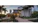 Luxury two-story home with landscaped grounds, a metal roof, and a brick paver driveway at 6934 Belgrave Dr, Siesta Key, FL 34242