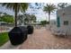 Outdoor grills with patio tables and chairs surrounded by palms and other tropical landscaping at 1660 Summerhouse Ln # 102, Sarasota, FL 34242