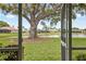 View from the screened porch, showcasing a lush backyard and lake at 1654 Waxwing Ct, Venice, FL 34293