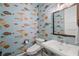 Whimsical powder room features a pedestal sink and toilet under quirky fish-themed wallpaper at 5005 Gulf Of Mexico Dr # 5, Longboat Key, FL 34228