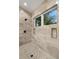 Luxurious shower featuring stone tile, rainfall shower head, built-in niche, and window with views of palm trees at 5005 Gulf Of Mexico Dr # 5, Longboat Key, FL 34228