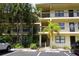 Multi-level condo building featuring private balconies, reserved parking, and lush landscaping with mature palm trees at 305 30Th W Ave # A103, Bradenton, FL 34205