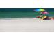 Couple relaxing on the beach under an umbrella on a sunny day at 100 Sands Point Rd # 305, Longboat Key, FL 34228
