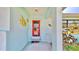 Inviting front entry with coral door, tile flooring, and whimsical fish decor at 1415 Piedmont Rd, Venice, FL 34293