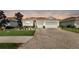 Attractive single-story home showcasing a brick driveway, tile roof, manicured lawn, and colorful landscaping at 1934 Mesic Hammock Way, Venice, FL 34292