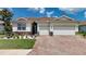 Attractive single-story home showcasing a brick driveway, tile roof, manicured lawn, and colorful landscaping at 1934 Mesic Hammock Way, Venice, FL 34292