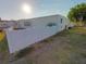 White single-wide mobile home with a white vinyl fence and mature trees at 4906 Sea Island Ave, Sarasota, FL 34234