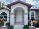 Front entryway with arched doorway and landscaping at 7430 Weeping Willow Dr, Sarasota, FL 34241